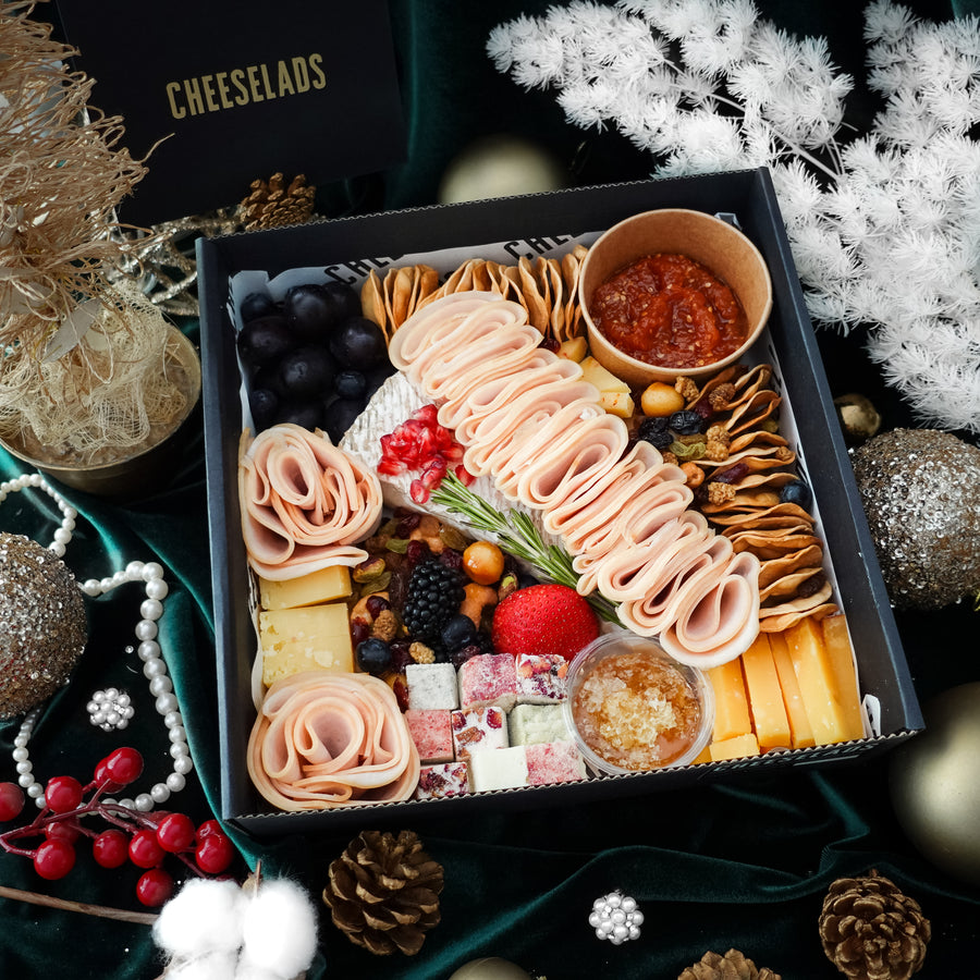 A box with meats, cheeses, olives, nuts, and a sprig of rosemary.