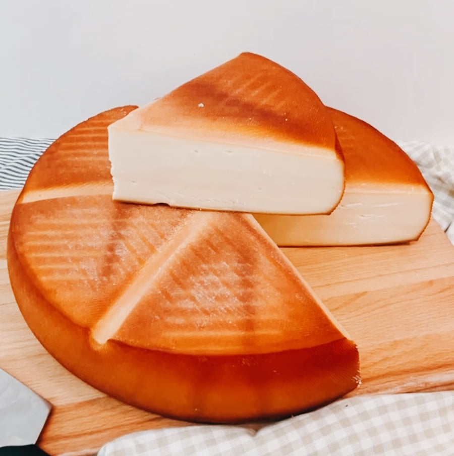 Cheese wheel with a slice on top.